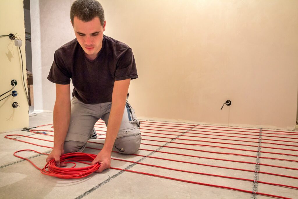 artisan installant un plancher chauffant électrique